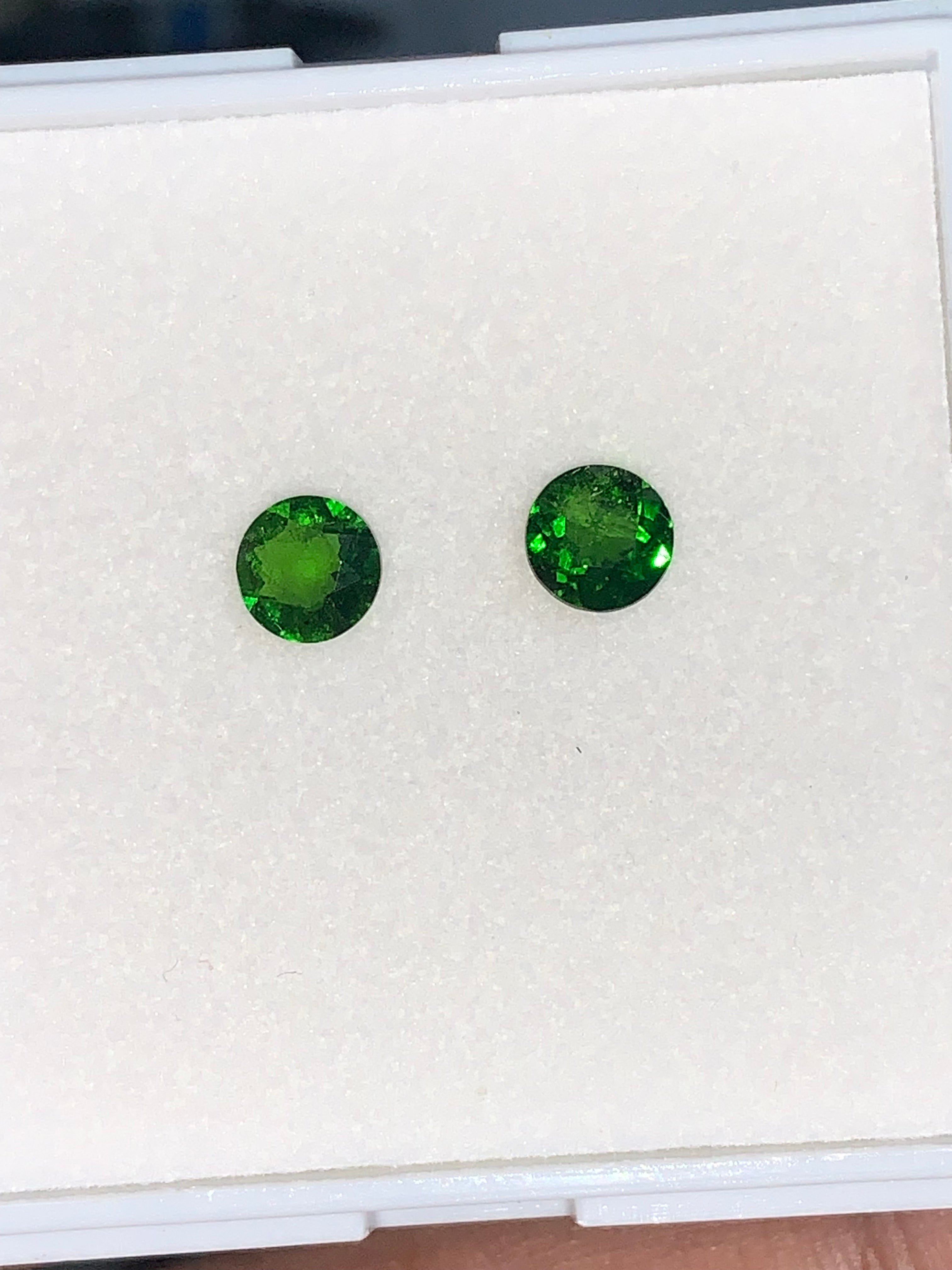 Two round cut green chrome diopside stones are presented against a white background, likely intended for jewelry making.