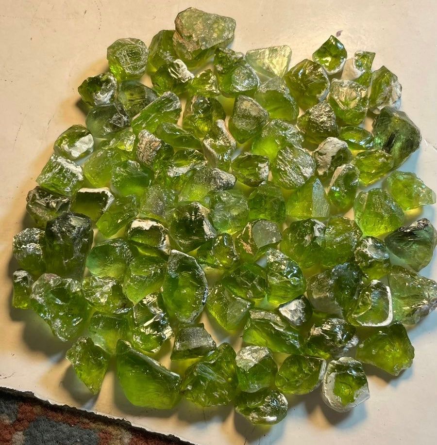 A collection of rough peridot stones displayed on a flat surface.